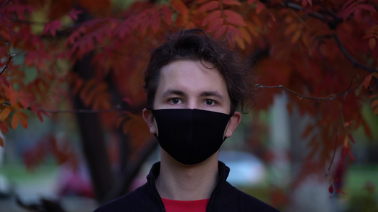 白天在城市街道上拍摄一名青少年的肖像他们戴着面罩对抗视频