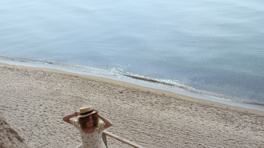 快乐的女人拿着草帽在木梯海滨阳光明媚的日子里纺纱视频