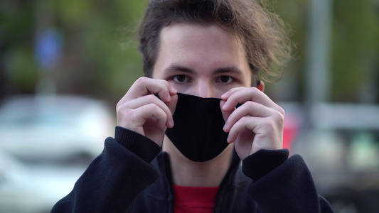 白天在城市街道上拍摄一名青少年的肖像他们戴着面罩对抗视频
