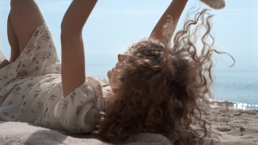 放松的女孩用草帽遮住脸躺在海滩上视频