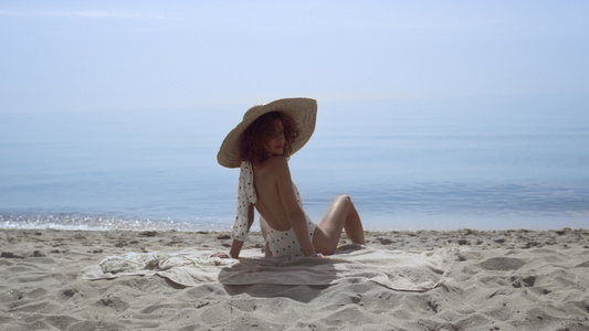 时尚的女人回头坐在阳光明媚的海边视频