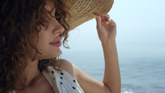 在阳光明媚的海滩上戴着宽边草帽的肖像豪华女人视频