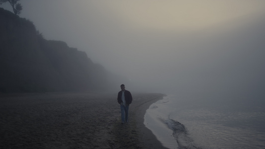 孤独的人在有雾的日出早晨在海滩散步视频