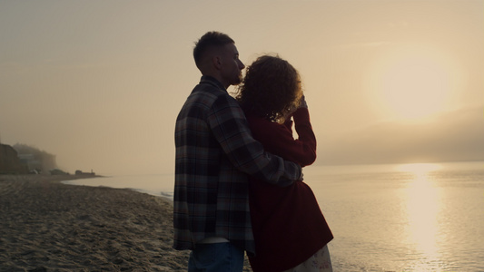 男人在日出时在海滩上拥抱女人视频