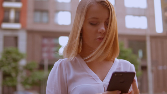 近近面面对金发年轻女人使用智能手机视频