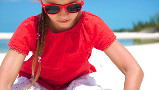 暑假时海滩上可爱小女孩的肖像快乐的孩子玩沙子慢动作视频