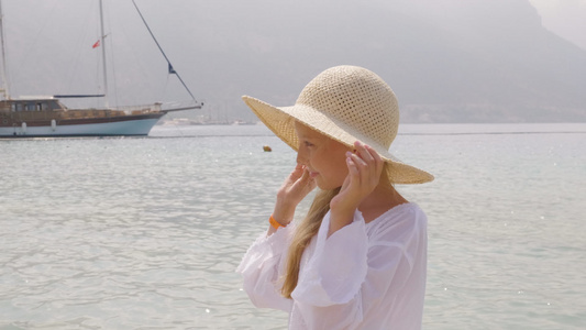 肖像女孩少年戴着草帽看海和船背景漂亮的女孩用手拿着视频
