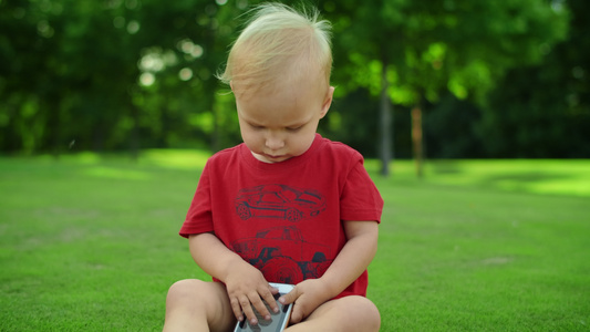 坐在绿色草地上可爱的孩子手持机视频