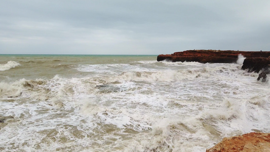 大海浪在岩石海岸破碎白泡沫在水面上视频