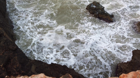 大浪撞向岩石高涨的岩石在沙滩上大量的白泡沫在风暴雨天视频