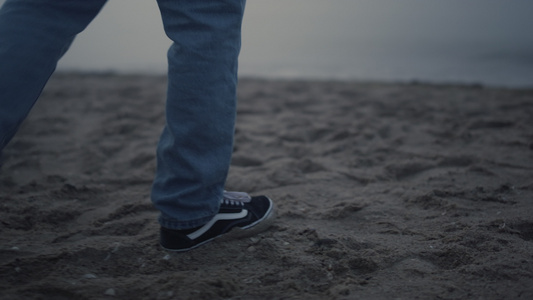 穿着时尚运动鞋走在沙滩上的家伙腿视频