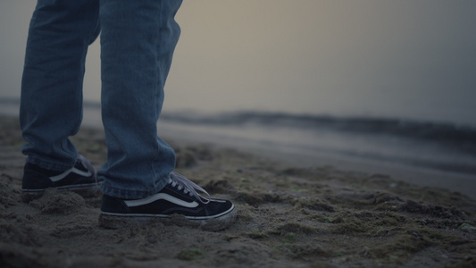 穿着运动鞋的男人腿站在海边视频