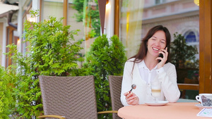 美丽的女人坐在户外咖啡馆喝咖啡和使用智能手机的画像16秒视频