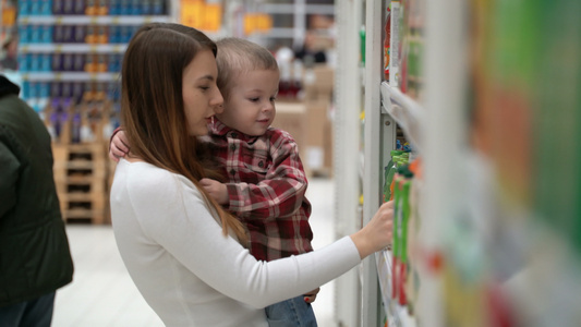 年轻母亲和儿子在商店里买水或果汁视频