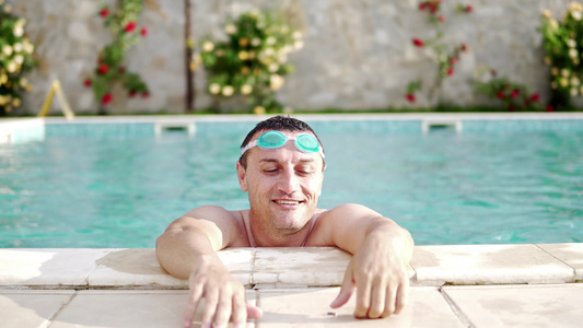在阳光明媚的一天长得帅和有谷歌的男人在游泳池里放松视频