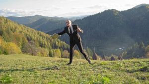 穿着西装和白衬衫的经理手拿着笔记本电脑在山上跳舞20秒视频