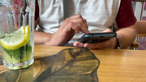 成年男子坐在咖啡厅的桌子上看着智能手机屏幕用手指触摸10秒视频