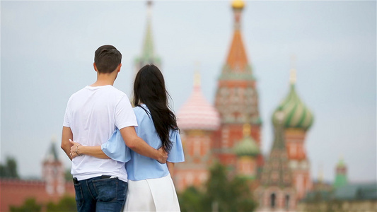 相爱的年轻情侣在城市背景下走在圣拜西尔教堂视频