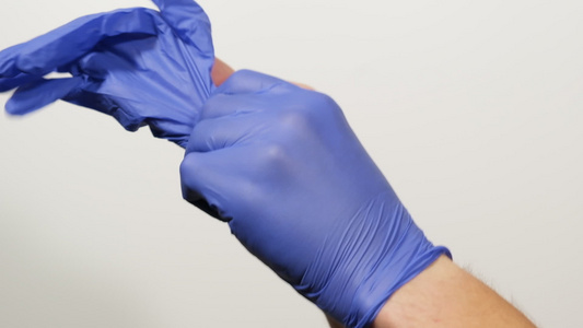 在流行和大流行期间将蓝色乳胶无菌手套戴在手上的过程视频