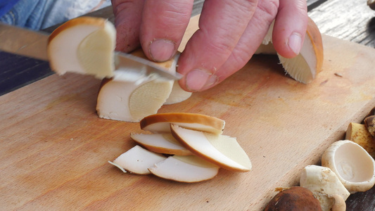 漂亮的野生蘑菇在木制砧板上用刀切成小块男子手在木桌上视频
