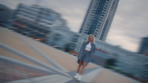 日落时站在市区现代建筑中的年轻女子16秒视频