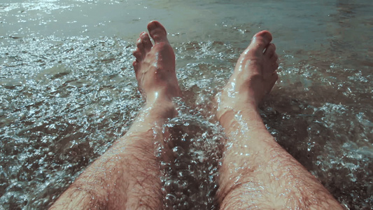 白人男子坐在水中他的腿被海滩的海浪冲刷视频