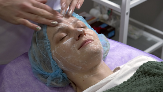 美容师把奶油涂在客户脸上进行按摩运动美容手术用乳霜视频
