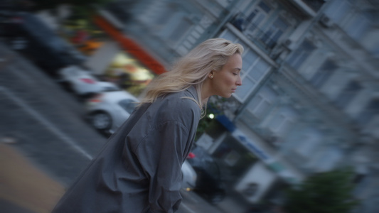 镇静的女人在晚上的城镇道路上与过往的汽车一起在城市散步视频