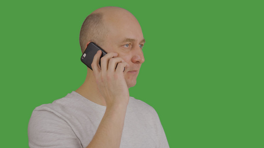 成人男子在绿色背景下听力和通过移动电话说话视频