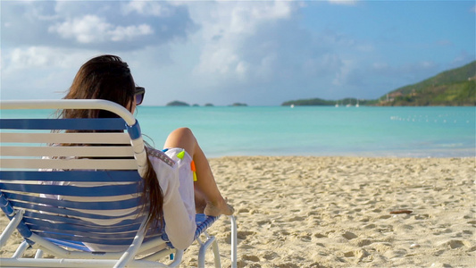 在暑假时放松和享受女人躺在沙滩上晒日光浴慢动作视频