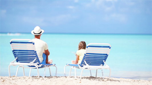 父亲和女儿在热带沙滩上坐着坐在长的花园里享受着亚特兰视频