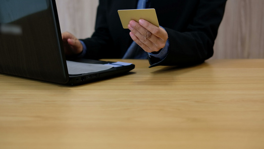 男子持信用卡使用电脑进行网上购物商人从互联网上购买视频