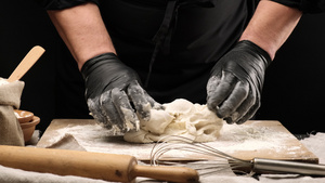 大厨用黑色面粉手套在木板上喷白小麦面粉面团17秒视频