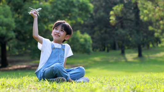 小朋友坐在草地上玩小飞机[小盆友]视频