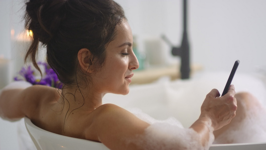 女人在浴缸里用智能手机打短信视频