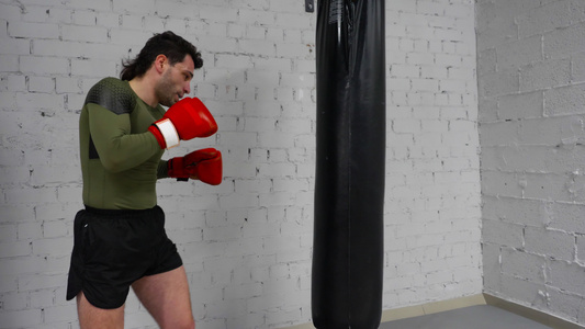 职业拳手正在体育馆训练用拳击袋踢打和拳头练习笑声视频