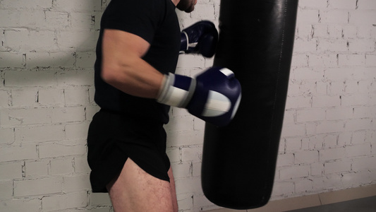 穿着黑色衣服训练腿的战斗机在拳击俱乐部踢到战斗袋手套视频