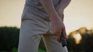 职业高尔夫球手手拿着俱乐部推杆在日落球道场上8秒视频