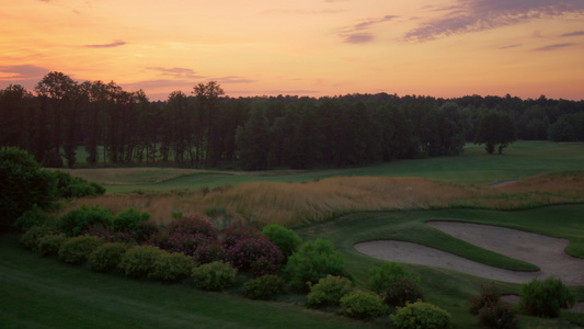 傍晚粉红色夕阳下的高尔夫球场鸟瞰图视频