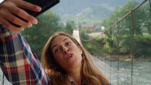 女游客在山区自然背景下使用手机自拍视频