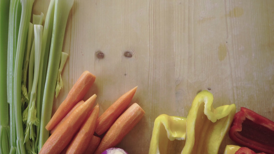 浅色木制工作台上的胡萝卜芹菜辣椒洋葱的顶视图镜头—视频