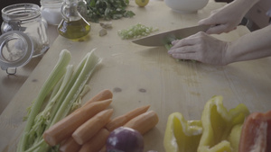 一位年轻女厨师在家庭烹饪中的浅色木制工作台上切芹菜23秒视频