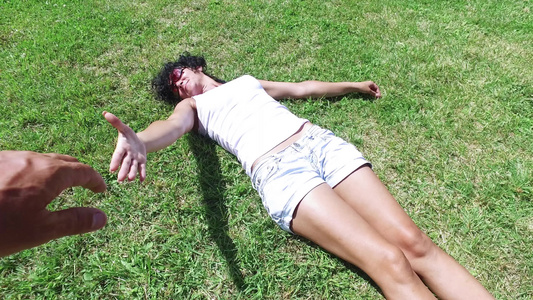 男人向一个躺在草地上帮助她站起来的漂亮女人伸出手四千视频