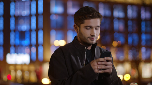 冷静的男人在黑暗街道上给手机发短信 放松的家伙打智能手机视频