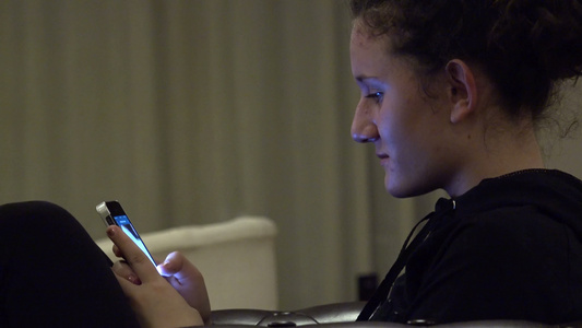 使用手机应用程序的智能手机女孩躺在旅馆大堂沙发上非常视频