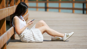 可爱女人坐在公园里时正在看手机短信的短信笑声15秒视频