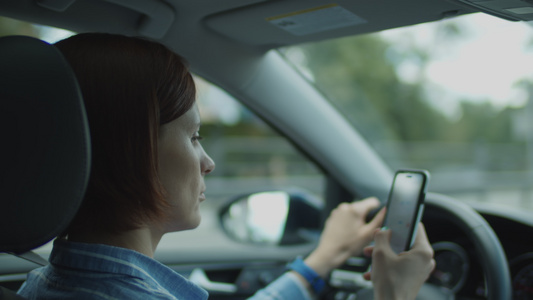 30多岁的女人开车手里拿着手机女司机拿着方向盘用手机视频