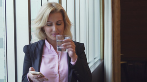 女商人喝水看手机照片在电话里18秒视频