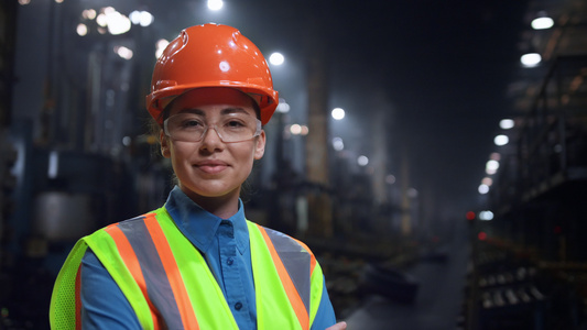 女工程师在巨大的工业仓库里戴着安全头盔微笑着拍照视频