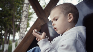 孩子坐在公园的长椅上看手机29秒视频